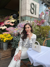 a lady wears a square neck striped knit top with white pants